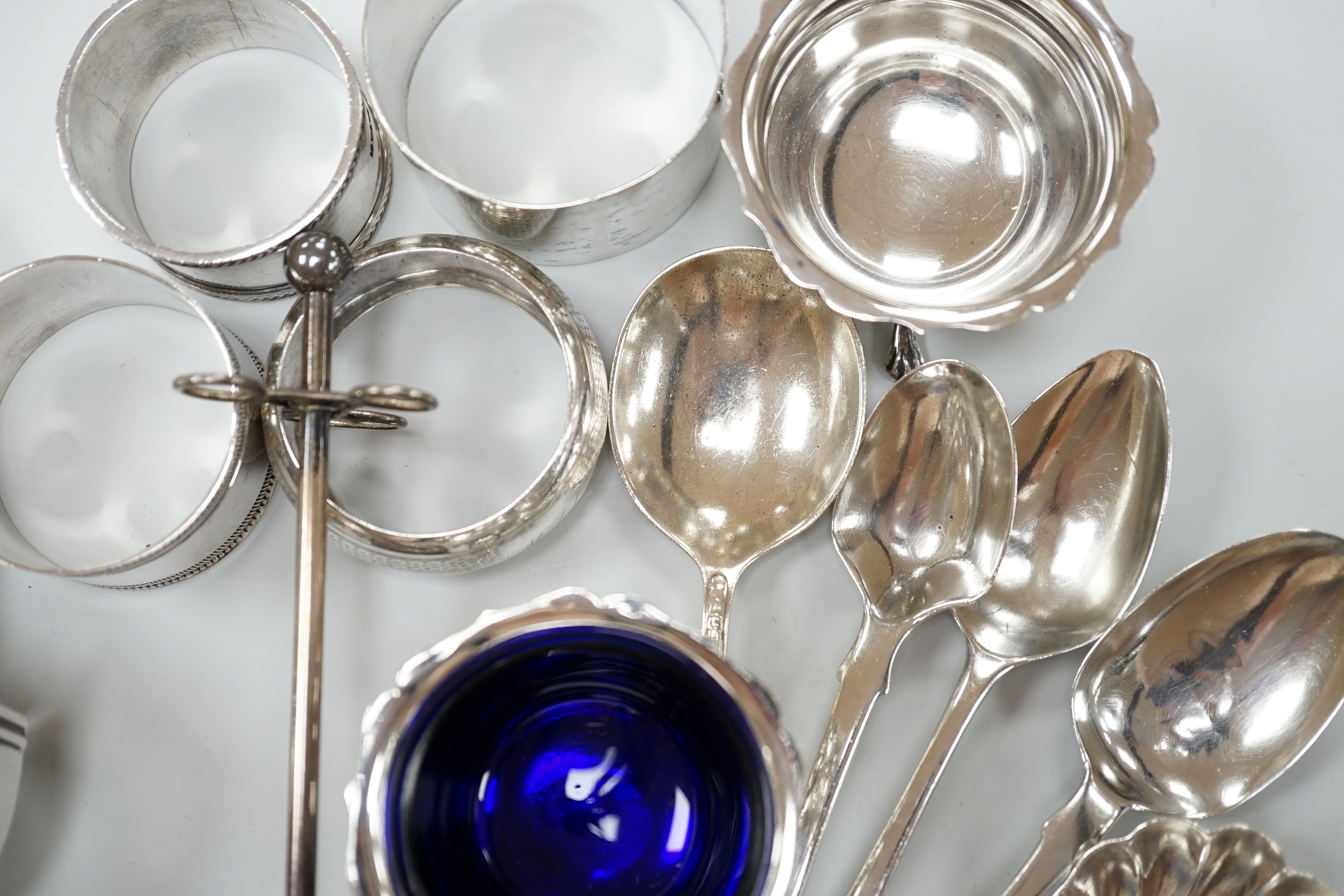 Sundry small silver including a George V pepperette, four silver napkin rings, a silver mounted implement stand, pair of salts (liner missing), four silver spoons and a George IV caddy spoon.